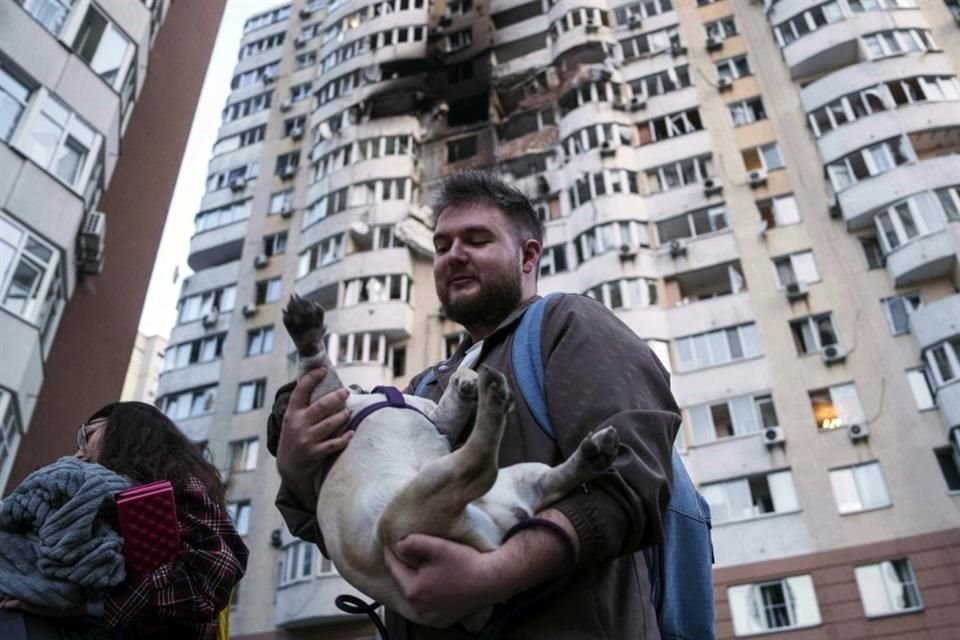 Un hombre sale con su perro en brazos de un edificio residencial de varias plantas dañado por el impacto de un dron ruso, en Kiev, Ucrania.