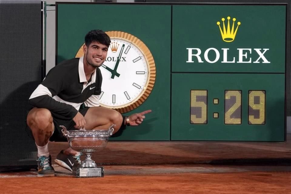 Carlos Alcaraz feliz con el trofeo e indicando la duración del partido.