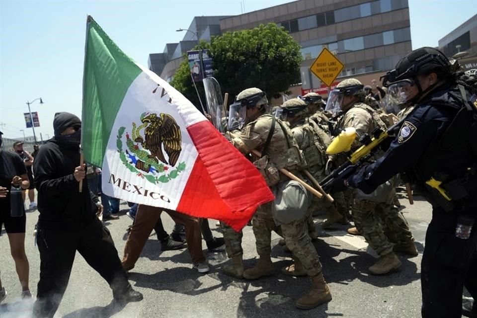 Manifestantes se enfrentan a las autoridades durante una protesta, luego de las redadas migratorios de anoche en Los Angeles.