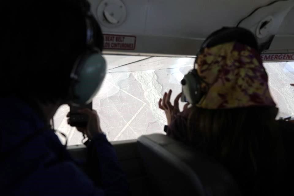Turistas toman fotos de las misteriosas líneas de Nasca durante un vuelo sobre la zona, desde donde se aprecian mejor las figuras.