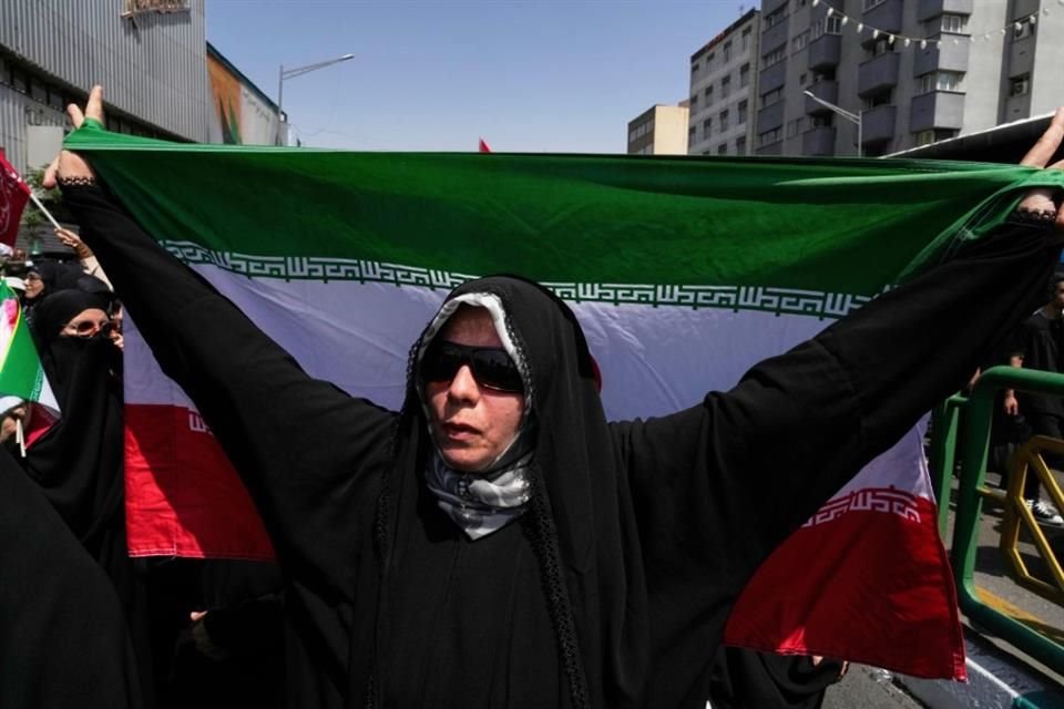Una mujer con la bandera iraní participa en una protesta en Teherán en contra de los ataques de Israel.