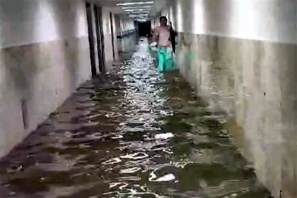 Una trabajadora camina con el agua hasta los tobillos en un pasillo del hospital.