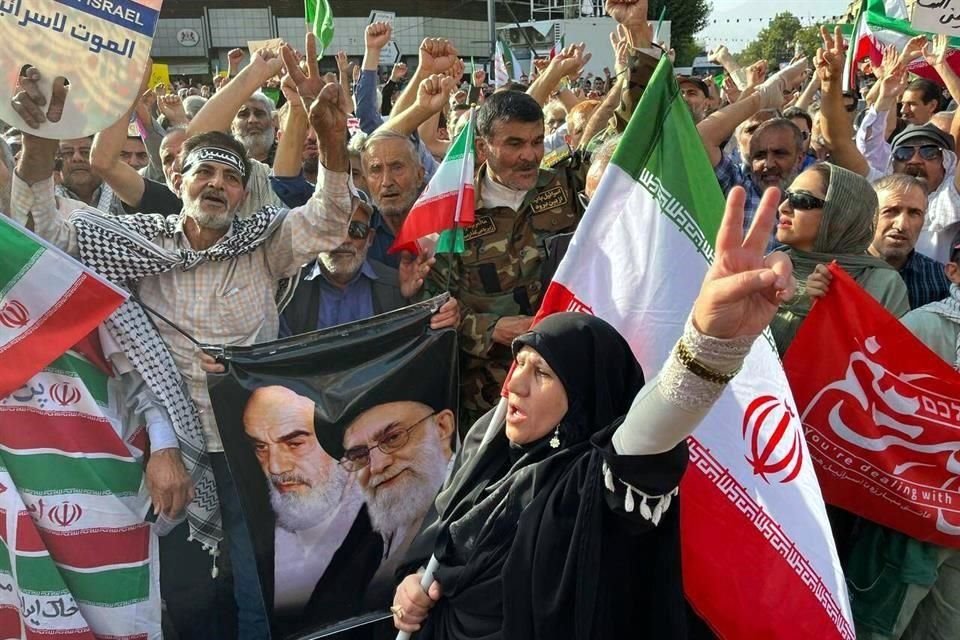 Manifestantes protestan en Teherán, tras el bombardeo de EU a instalaciones nucleares de Irán; los manifestantes llevan   banderas iraníes y pósters de líderes de la revolución iraní.