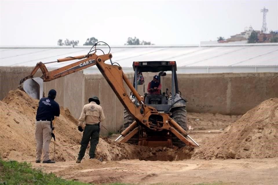 Con el apoyo de dos máquinas retroexcavadoras, los especialistas remueven la tierra en una zanja que habría sido realizada para el drenaje de un fraccionamiento en construcción.
