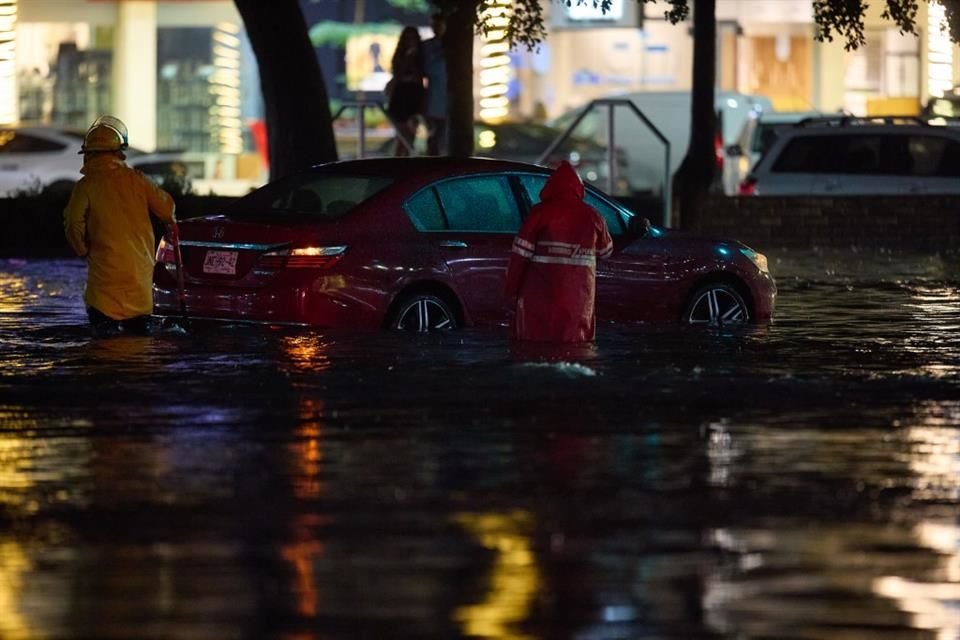 Personal de Bomberos de Zapopan auxilia a personas que quedaron atrapadas dentro de su vehículo durante la tormenta del jueves.