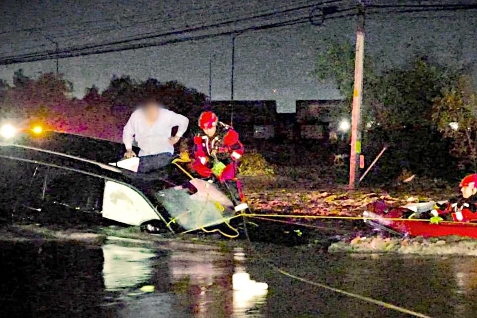 Con lancha y cuerdas, rescatistas atendieron a personas atrapadas en sus autos por las inundaciones.