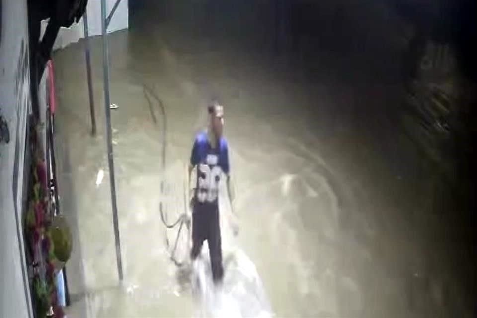 Guillermo Martínez Santana camina amarrado de una manguera para ir a salvar a Martha Ortiz que estaba atrapada en su vehículo.