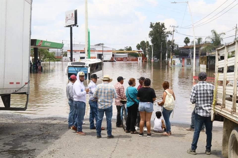 Varias personas aguardaban a que bajara el nivel del agua para poder cruzar a su destino.