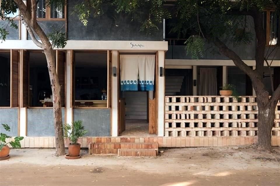 La fachada del hotel se encuentra cubierta por árboles frondosos.