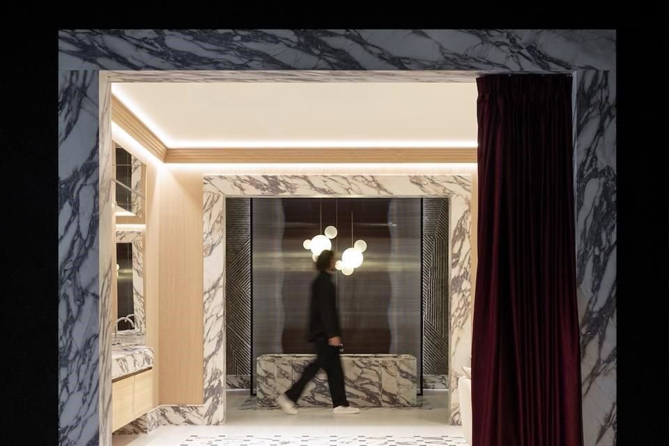 Una cortina como un telón teatral se abre para revelar el interior de un departamento lleno de evocaciones y detalles de ambientación.