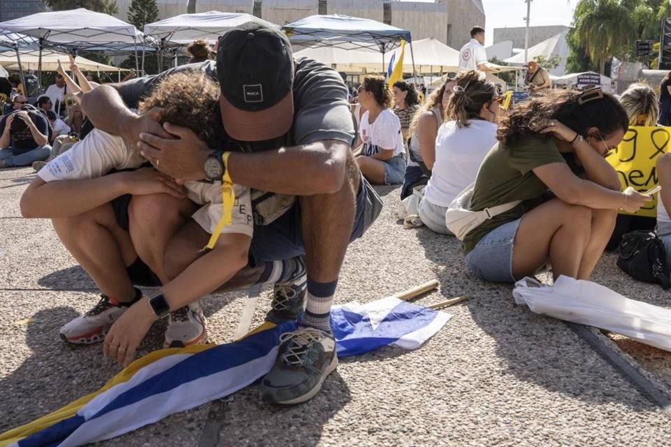 Personas se sientan en el piso y se cubren la cabeza luego de que sonaran las sirenas de alarma por un misil disparado desde Yemen, en medio de una manifestación por los rehenes.