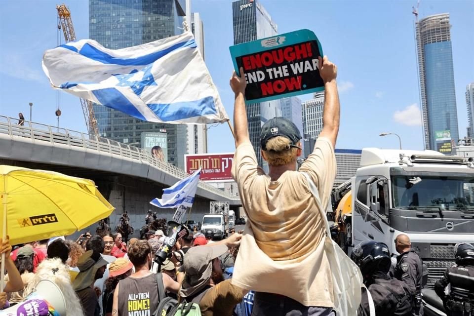 Una persona alza una pancarta que dice: 'Suficiente. Acaben la guerra'.