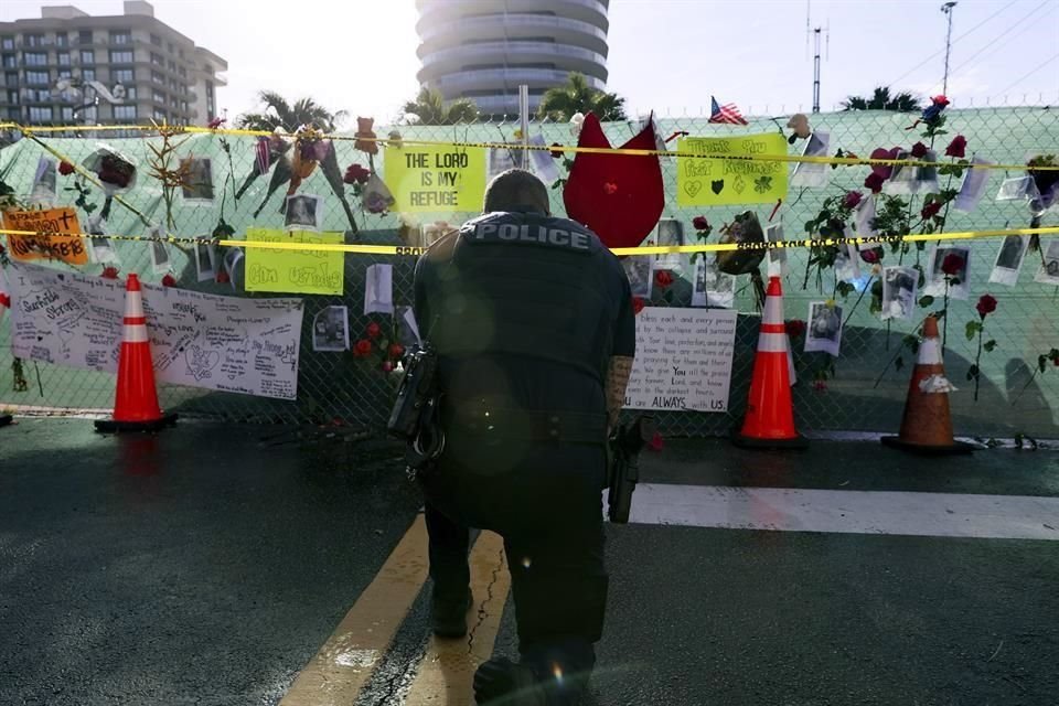 Un policía de Miami se arrodilla frente al memorial de las víctimas y desaparecidos por el colapso.