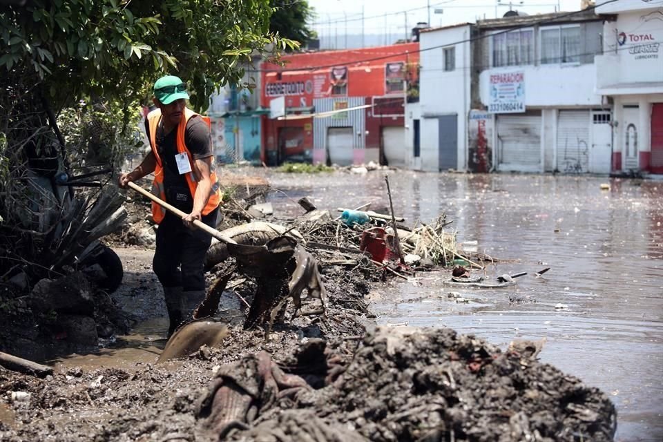 Vecinos junto con personal de Protección Civil trabajan en retirar los escombros y lodo que dejó el desbordamiento del arroyo El Seco.