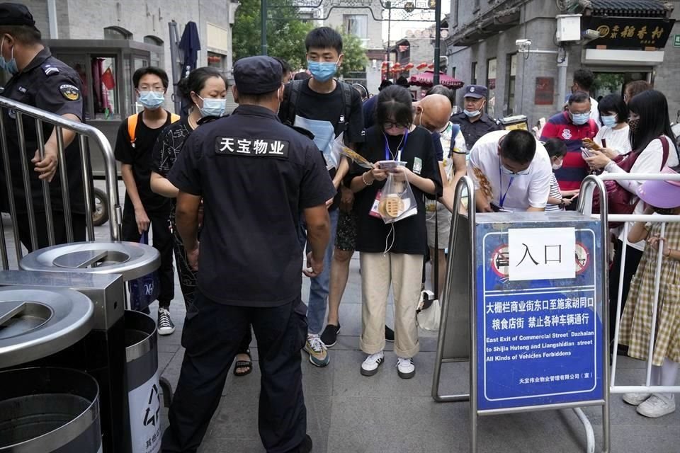 Personas en Beijing muestran su pase de salud electrónico a un guardia.